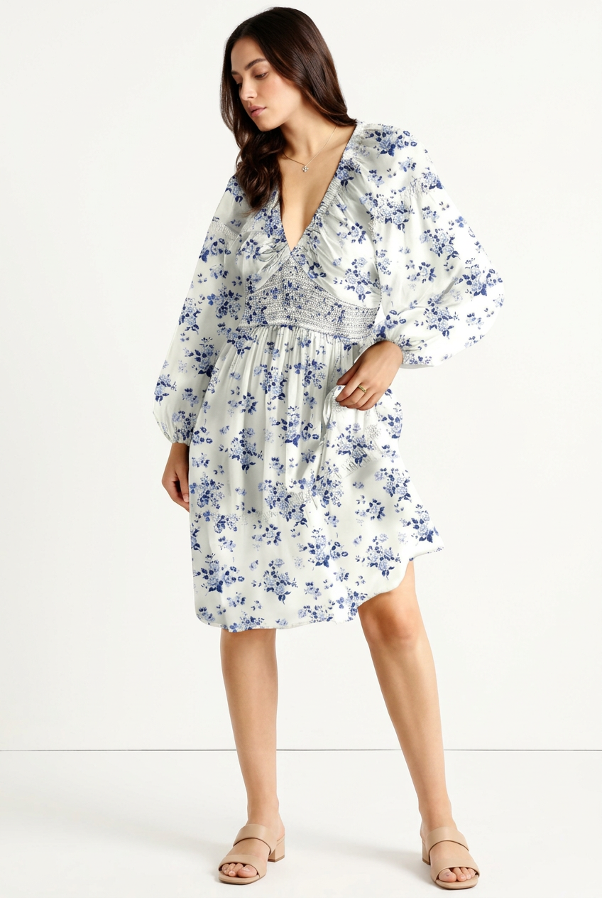 White and blue floral V-neck mini dress with smocked waist and long sleeves, full-body front angled view